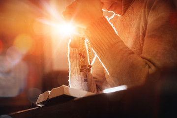 Wall Mural - Christian woman praying in church. Hands crossed and Holy Bible on wooden desk.