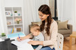 motherhood, multi-tasking, family and people concept - happy mother with baby, papers and laptop working at home
