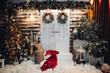 Front view of stylish decorated studio for Christmas holiday, with big white doors in center of wall. Exterior of house preparing for x mas. Christmas tree, many presents and pine.