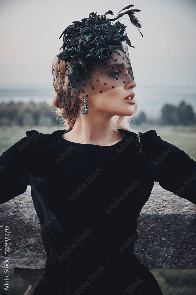 Amazing outdoor portrait of beautiful woman in black dress and dark green  fascinator with veil. Victorian look. Stock Photo | Adobe Stock