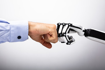 human hand and robot making fist bump