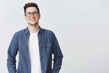 waist-up shot of happy friendly-looking handsome young smart male coworker in glasses and blue shirt