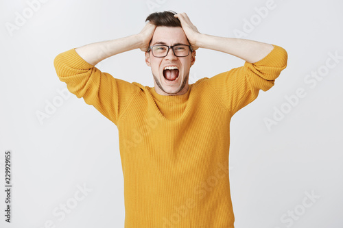 Cuadros en Lienzo Man yelling cannot control panic and stress holding hands on head open mouth and
