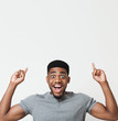 © Prostock-studio - Excited african-american man pointing upwards at copy space