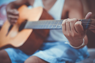 man's hands playing acoustic guitar, close up