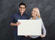 Young couple holding blank white banner