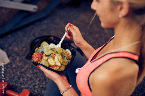 Fotomural Top view of woman eating healthy food while sitting in a gym