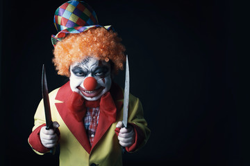 Halloween. Scary clown with knives. 