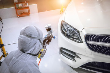 Staff wear Chemical protective clothing at work.Car Care Business. Automobile industry. Car wash and coating business with ceramic coating.Spraying the varnish to the car.