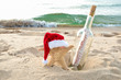 starfish with Santa cap in beach sand with happy holiday message in a bottle