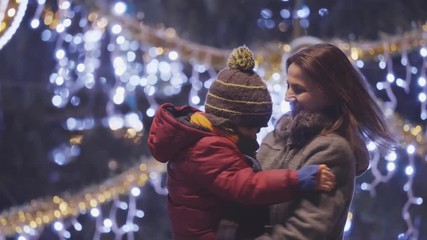 Wall Mural - Portrait of mother and child dancing in front of Christmas tree outdoors