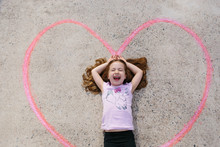 Cute Young Girl Laying In A Chalk Drawn Heart On The Ground