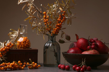 Autumn still life with sea buckthorn, hawthorn berries and apples. Composition of various berries and fruits in interior. 