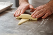 Hands rolling dough into croissants