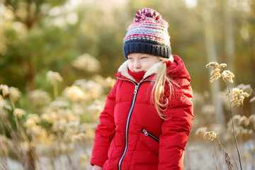 adorable little girl having fun in beautiful winter park. cute child playing in a snow.