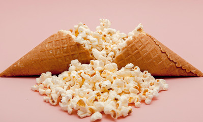 Popcorn in ice cream cones on pink background