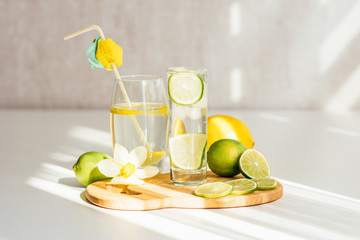 two glasses with water and lime on a wooden board, sliced lime and narcissus flower