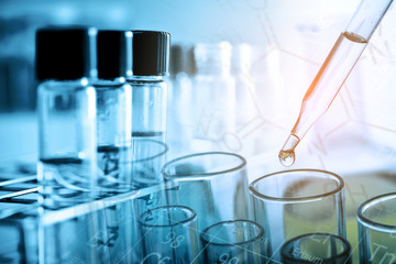 Wall Mural - dropping chemical liquid to test tube with lab glassware background. science or chemistry research a