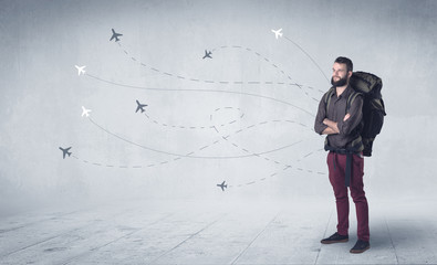 Wall Mural - Handsome young man standing with a backpack on his back and little planes in the background