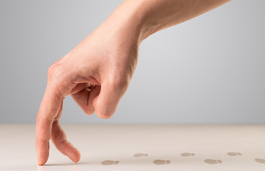 Female fingers walking with footsteps behind them 