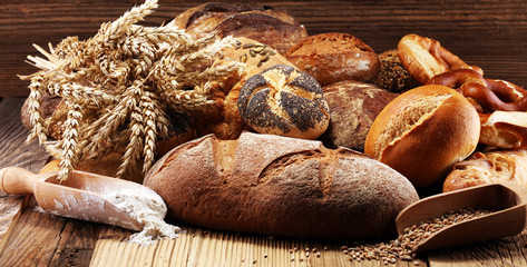 Different kinds of bread and bread rolls on board from above. Kitchen or bakery