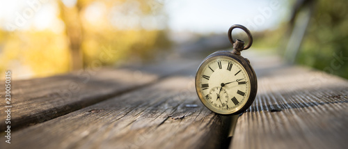 Cuadros en Lienzo Retro Taschenuhr auf Holzbank, Himmel und bunte Blätter im Herbstlicht, Symbol f