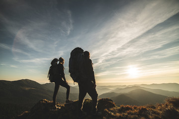 Wall Mural - the couple standing on a mountain with a picturesque sunset background