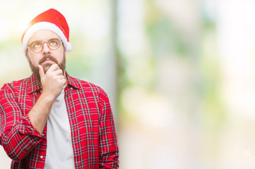 Poster - Young caucasian man wearing christmas hat over isolated background with hand on chin thinking about question, pensive expression. Smiling with thoughtful face. Doubt concept.