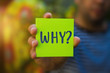 Hand holding a green Paper with the word why against blurred background - Why?, Business Concept