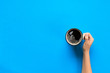 Minimalistic style woman hand holding a mug of coffee on background. Flat lay, top view