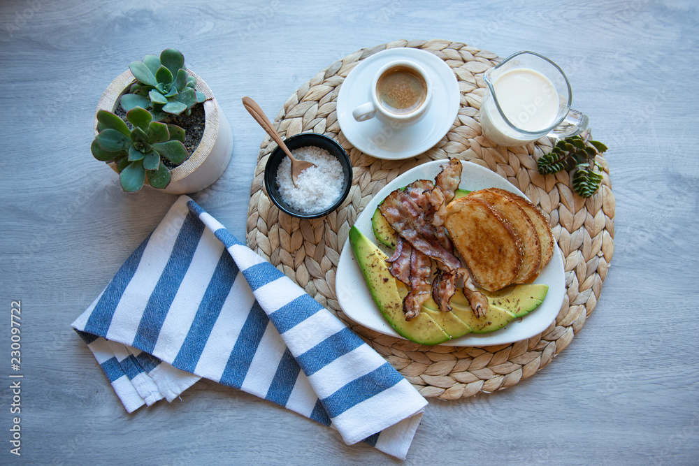 Fried bacon on white plate with cup of coffee and milk jug
