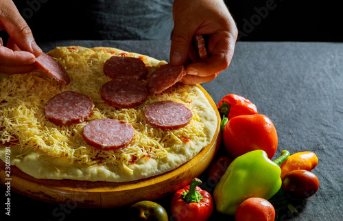 Fotografie, Obraz Chef prepares delicious pizza cooking, sausage salami, thick dough, pizza crust