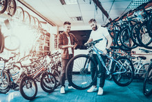 Consultant Shows Bicycle To Client In Sport Shop
