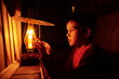 © EvgeniiAnd - boy reading in the light of an old lamp. the child sitting on a dark staircase with a book