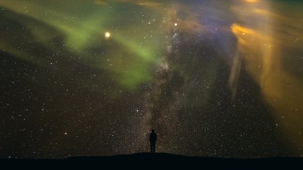 Wall Mural - The man standing on a background of starry sky with a northern light. time lapse