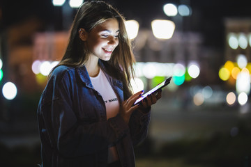 Wall Mural - Beautiful young woman using tablet in the city at night bokeh