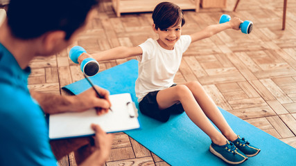 Male Trainer and Boy with Dumbbells Sits on Floor.