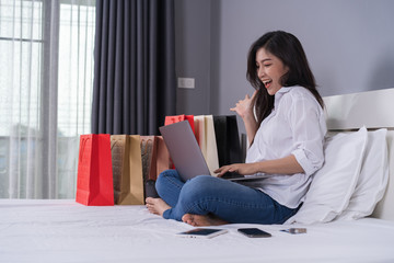 Sticker - cheerful woman using laptop computer to shopping online on bed