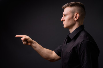 Profile view of young handsome businessman pointing finger