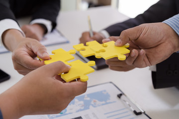 Group of business partners assembling jigsaw puzzle.