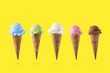 Variety of ice cream flavor in cones blueberry ,strawberry, green tea, chocolate and coconut setup on yellow background . Summer and Sweet menu concept.