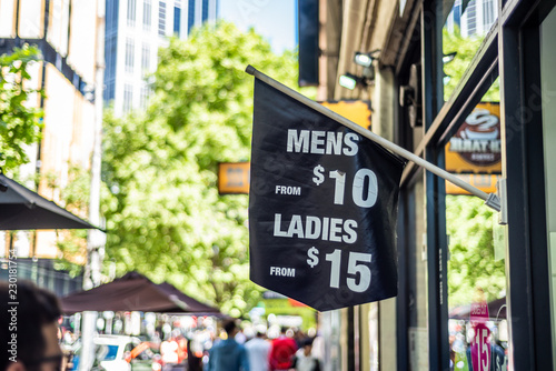 A Sign With Mens And Ladies Hair Cut Prices On A City Street In