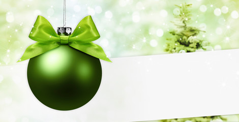 merry christmas signboard or gift card, ball with green ribbon bow on blurred green xmas lights and 