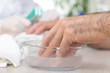 Męska dłoń moczy się w misce z wodą w salonie kosmetycznym. Przygotowanie do zabiegu manicure.