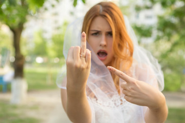 Sexy brunette caucasian woman in white wedding veil and dress. She pointing on her ring finger, shocked troubled expression on her face. Copy space