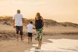 Fototapeta Sport - Family walking on beach sand in the sun. Nice family reunited if summer vacation