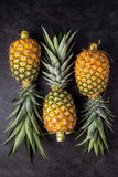 Three Fresh ripe pineapple on dark background, vertical composition , top view
