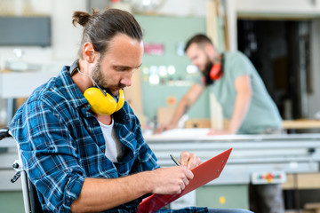 Wall Mural - worker in wheelchair in a carpenter's workshop with his colleagu