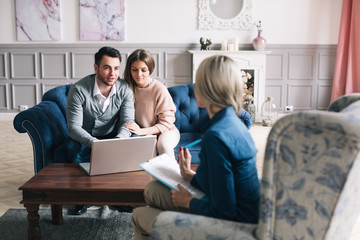 Happy young loving couple sitting together with their financial advisor.