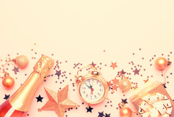 Christmas or New Year composition, frame, pink background with gold Christmas decorations, stars, snowflakes, balls, alarm clock, gift box and bottle of champagne, top view